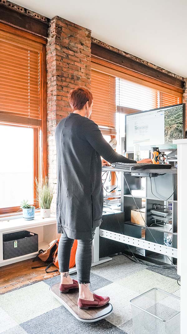 Shannan standing at her desk on a balance board.